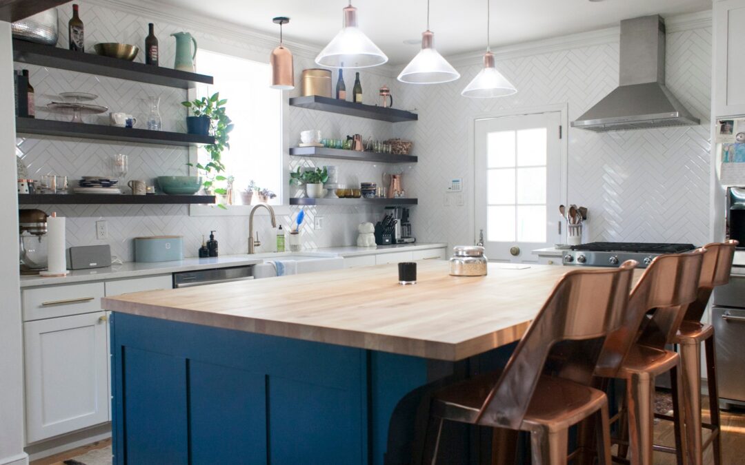 A light, bright kitchen with an island that has a dark blue base.