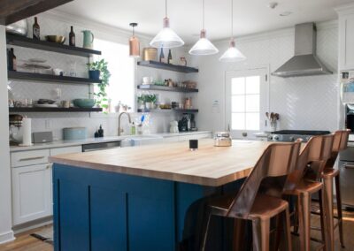 A light, bright kitchen with an island that has a dark blue base.