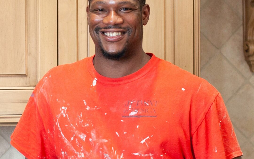 A Tulsa interior Painter smiles at the camera with white paint on his orange shirt.