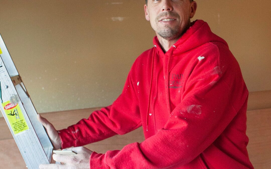 A Tulsa Interior Painter in a red hoodie climbing a ladder.