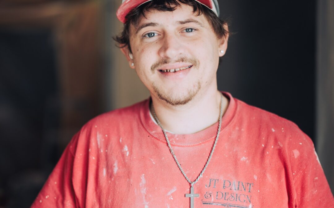 A Tulsa interior Painter smiles at the camera with white paint on his orange shirt.