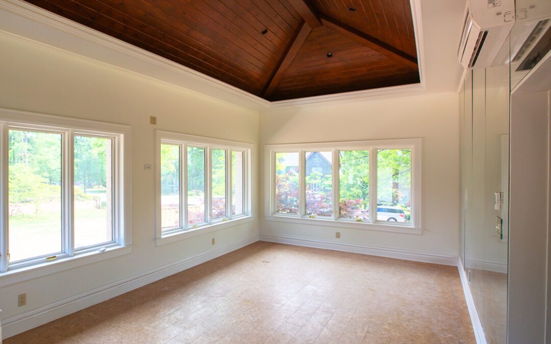 An empty living room lined with windows and clean, freshly painted white walls.