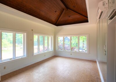 An empty living room lined with windows and clean, freshly painted white walls.