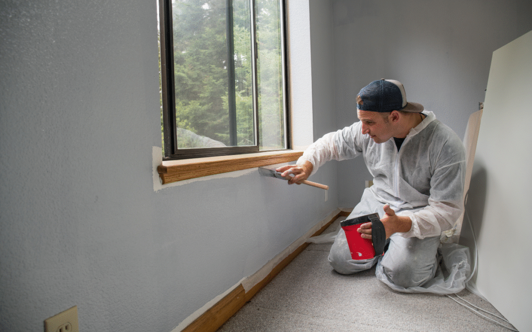 Man painting a wall below a window
