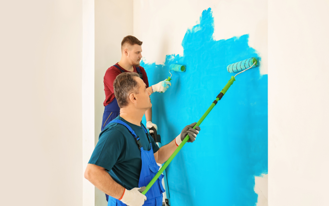 Two men painting a wall with paint rollers