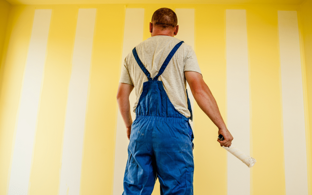 Painter standing in front of a wall inspecting their work